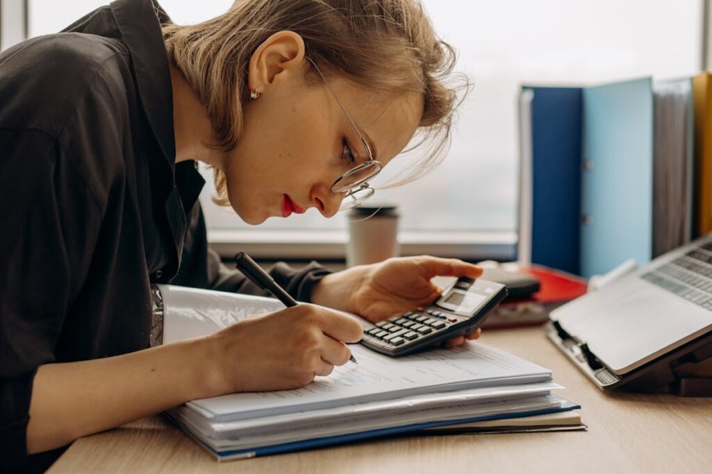 Young woman diligently working on accounting with a calculator and documents. Perfect for business and finance themes. Organize Your Digital Files