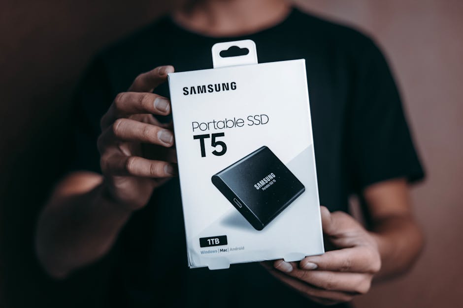 Close-up of a person holding a Samsung T5 Portable SSD box, emphasizing modern technology. organize you digital files with backup