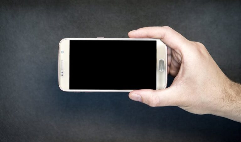 Close-up of a hand holding a smartphone with a blank screen, ready for design mockup.