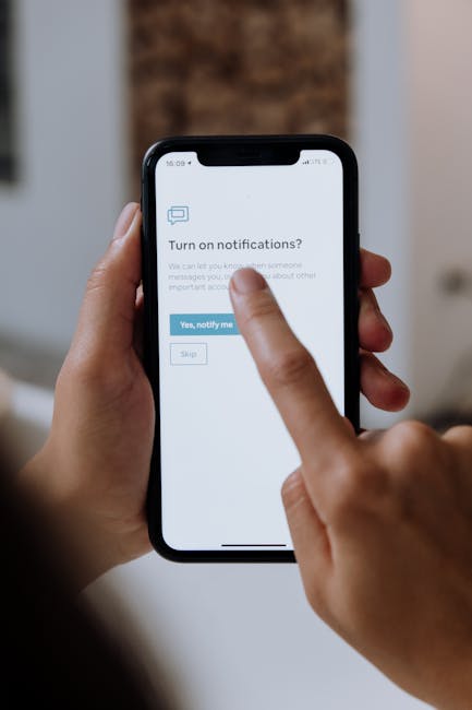 Close-up of hands using a smartphone for digital notification setup.